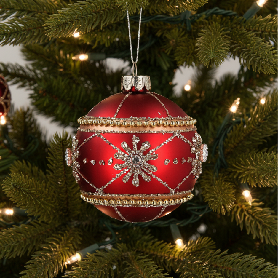 Decorative red Christmas ball ornament with gold and silver details on a tree.