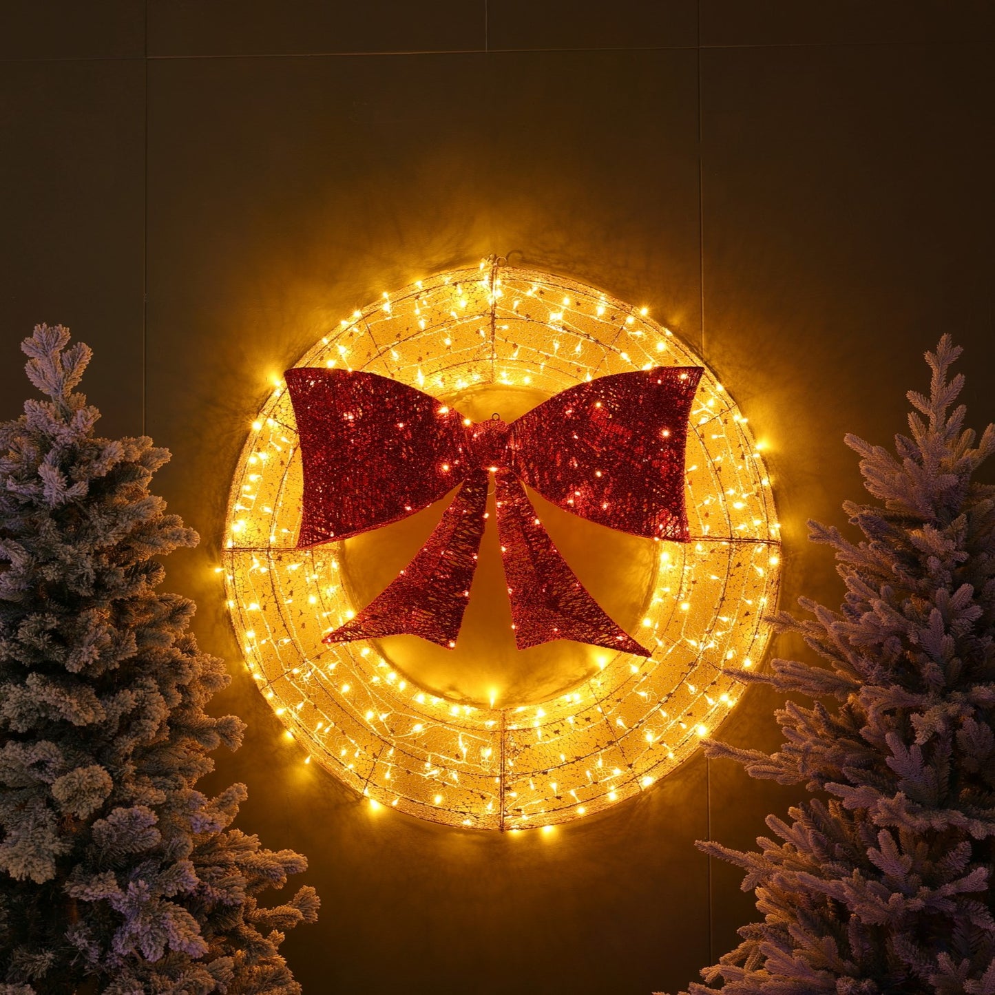 Decorative wreath with red bow and string lights against a dark background