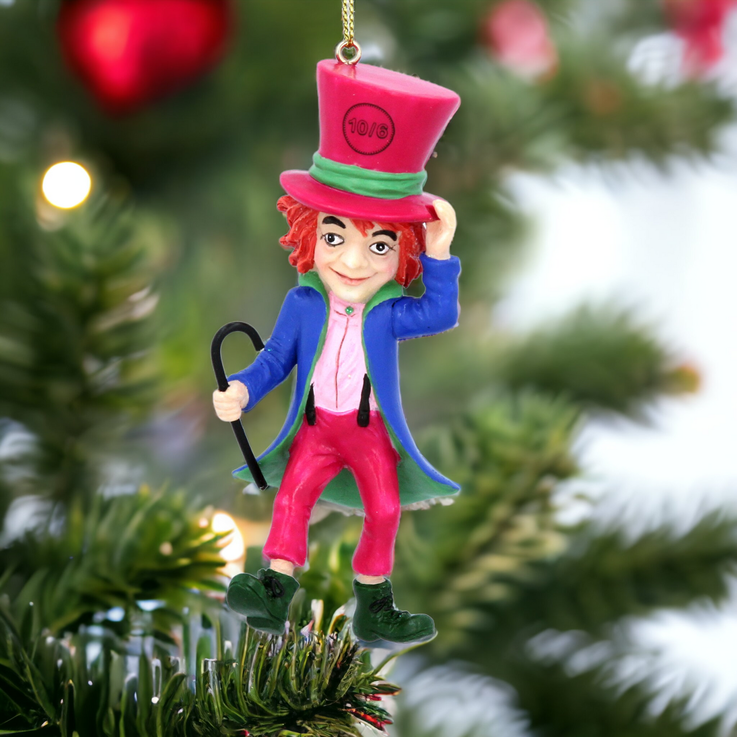 A hanging decoration featuring a colorful version of the Mad Hatter from Alice in Wonderland, with a red jacket, green pants, a pink top hat, and a black cane.