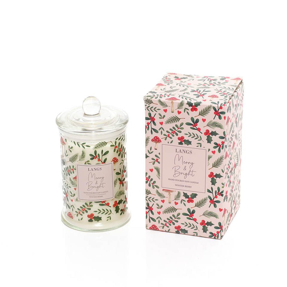 A Langs Merry & Bright scented candle in a clear glass jar with a lid, shown next to its matching floral-patterned packaging box on a white background.