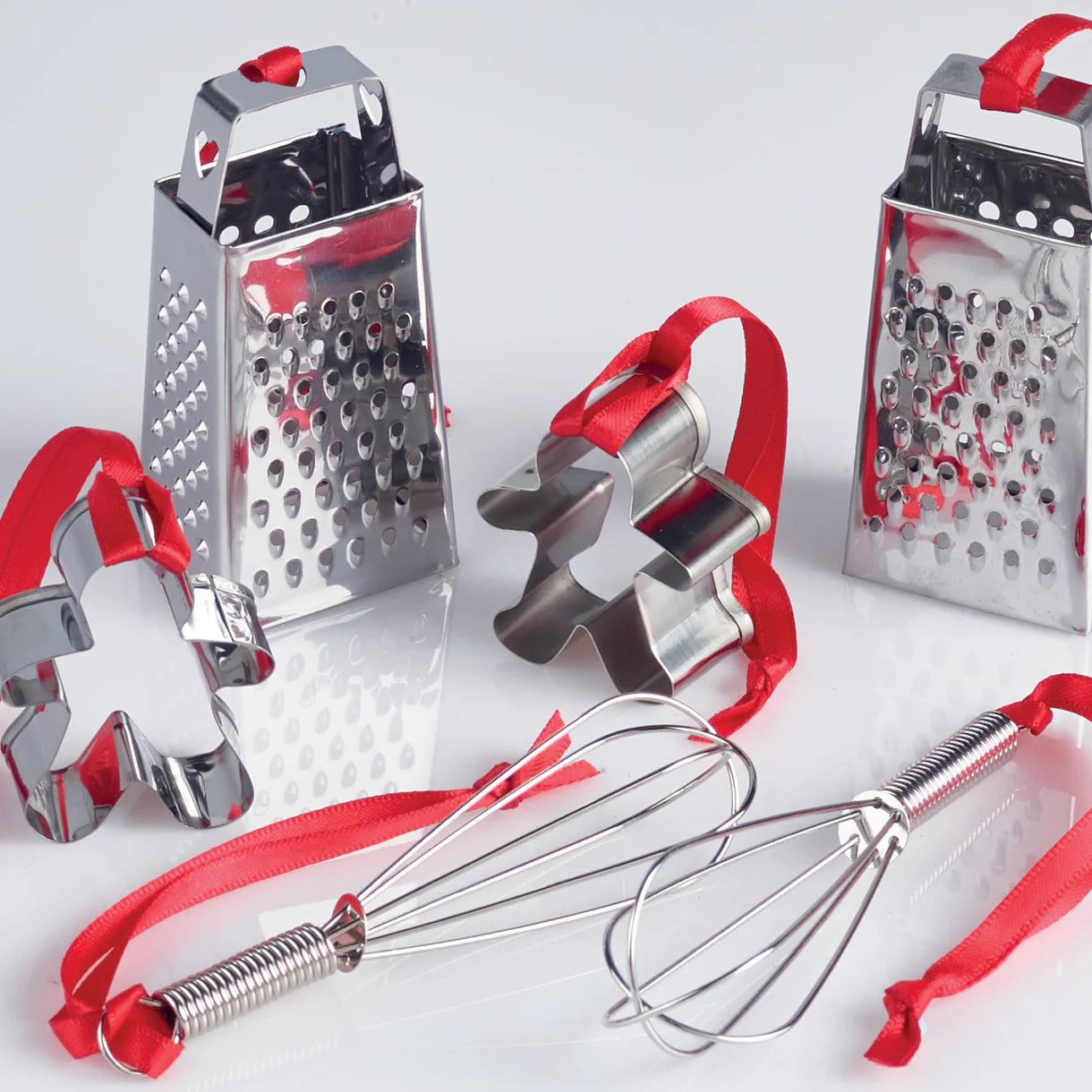 Set of kitchen tools including a box grater, whisk, and cookie cutters on a white background