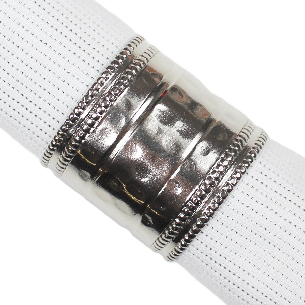 A close-up of a polished silver-toned metal ring with decorative beaded bands, shown wrapped around a white textured napkin.