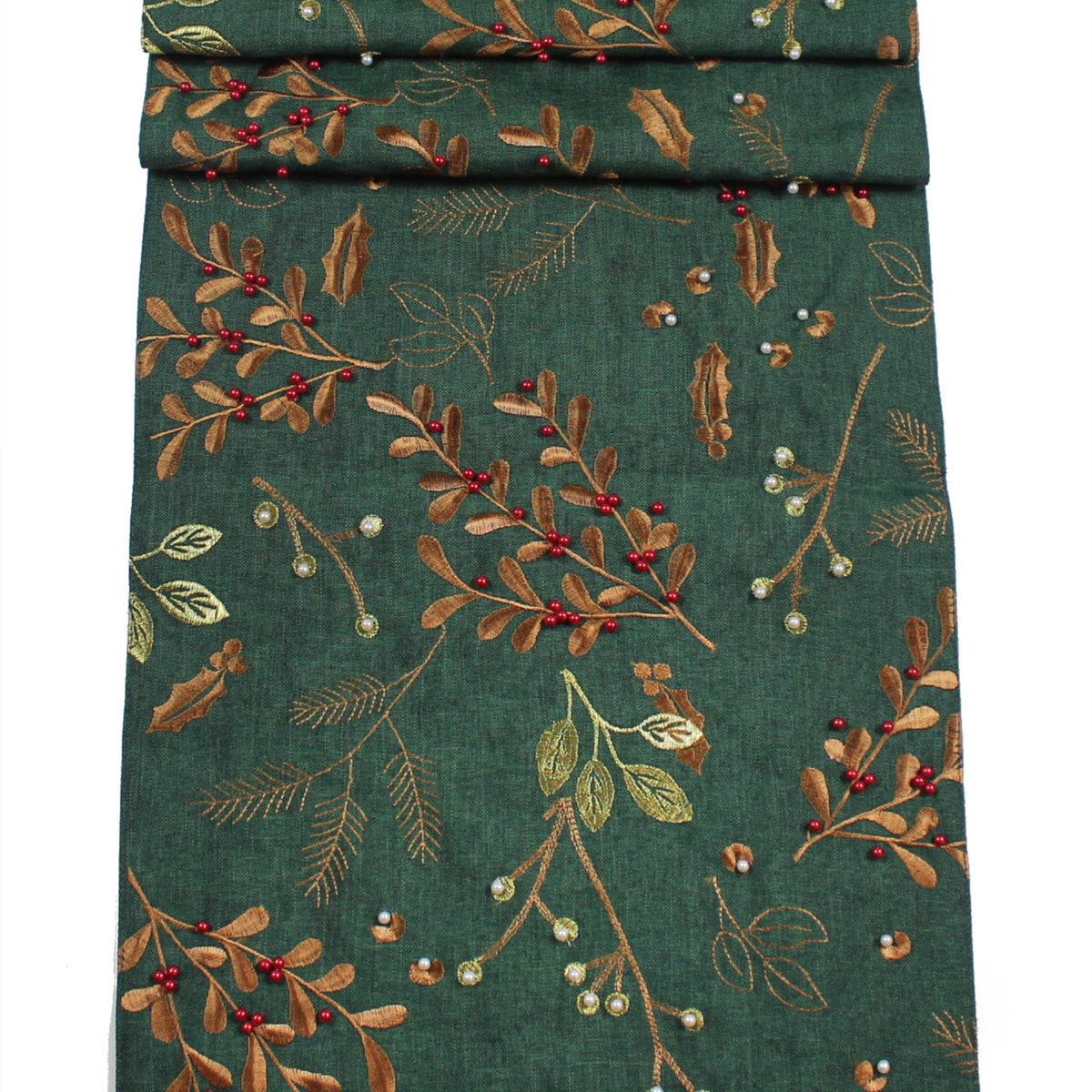 A folded dark green fabric table runner featuring an embroidered botanical pattern of holly leaves, berries, and pine branches in brown, gold, and red.