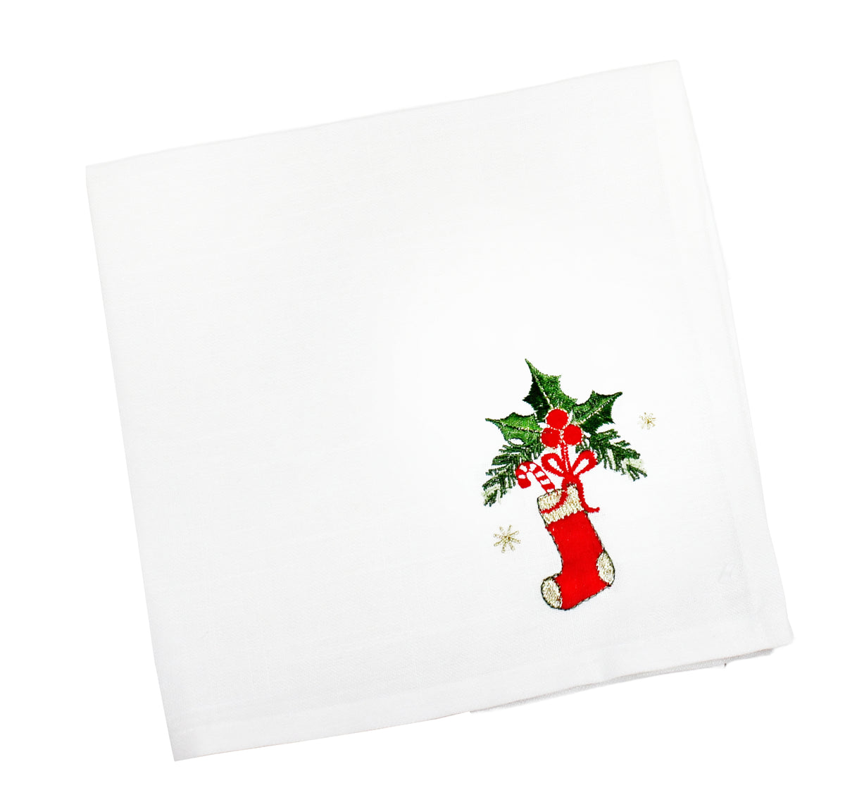 A white square fabric napkin featuring an embroidered Christmas design in the lower right corner, including a red stocking, green holly leaves, red candy canes, and small gold stars.
