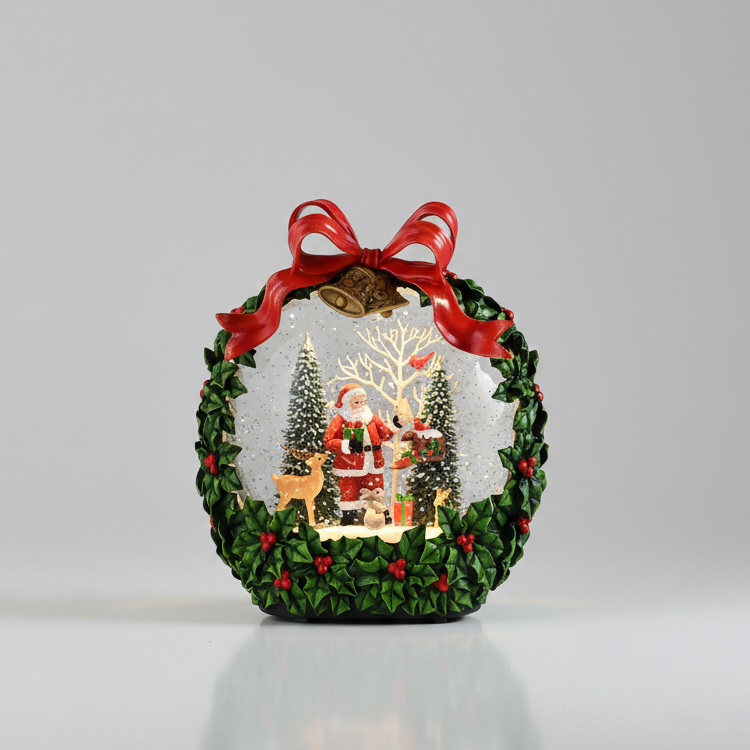 A decorative Christmas snow globe ornament featuring a green wreath border with red berries, a red ribbon bow, and a miniature festive scene inside with Santa, trees, reindeer, and warm lights, photographed on a clean light gray background.