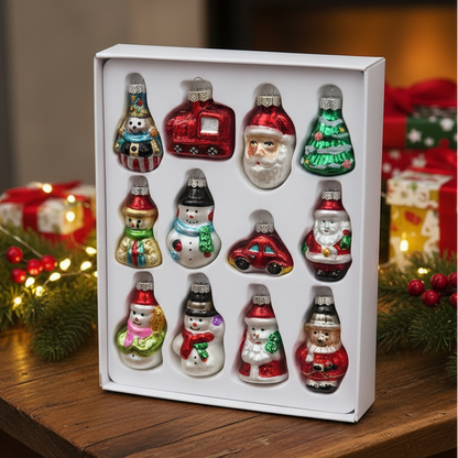 A white box containing 12 small glass Christmas ornaments shaped like snowmen, Santa Claus, and holiday vehicles, displayed on a wooden table with festive decorations in the background.