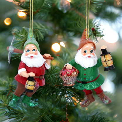 Two resin dwarf hanging decorations for Christmas trees, one red with a pick axe and one green with a basket, surrounded by lights and pine needles.