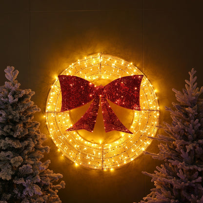 Decorative wreath with red bow and string lights against a dark background