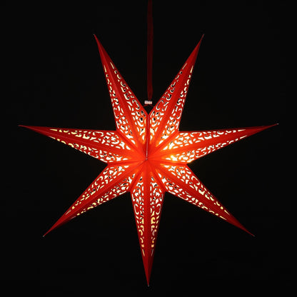 A glowing red seven-pointed paper star lantern with intricate cutout patterns, suspended against a solid black background.