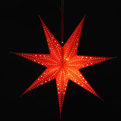 A glowing red seven-pointed star hanging ornament with small star-shaped cutouts, suspended against a solid black background.