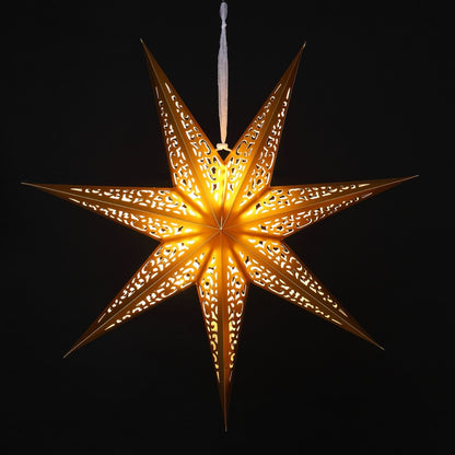 A glowing seven pointed paper star Christmas ornament with intricate laser-cut patterns, emitting a warm golden light against a solid black background.