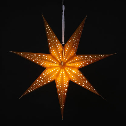 A glowing seven-pointed star Christmas ornament with small cutout windows, suspended by a white string against a solid black background.