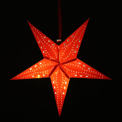 A glowing red five-pointed star hanging ornament with small cutout details, shown against a solid black background.