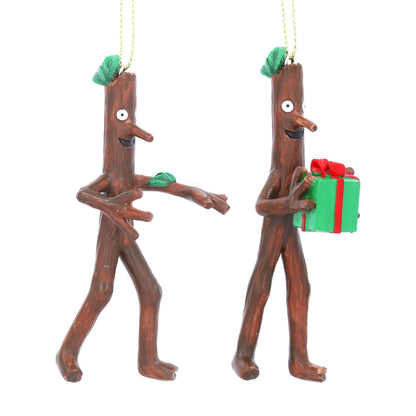 Two resin stick figure ornaments, one holding a gift, on a white background.