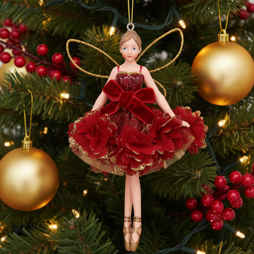 A ballet fairy Christmas ornament featuring a female figure in a red velvet and tulle tutu dress with gold accents, gold wire wings, and a hanging loop, shown against a Christmas tree background.