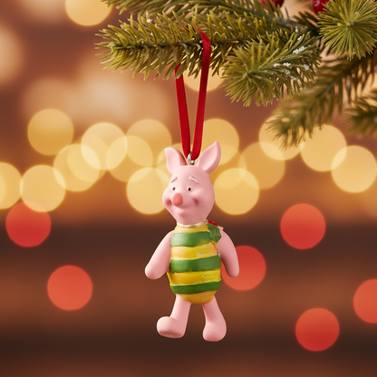 A Piglet Christmas ornament hanging from a green Christmas tree branch with a red ribbon, set against a warm, blurred lights background.