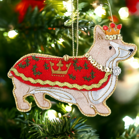 A fabric Christmas hanging decoration featuring a stylized corgi dog wearing a red crown and scepter, with a green and red background.