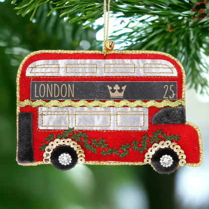 A fabric hanging Christmas tree decoration shaped like a red double-decker bus with 'London 25' written on the side, adorned with gold trimmings and sequins.