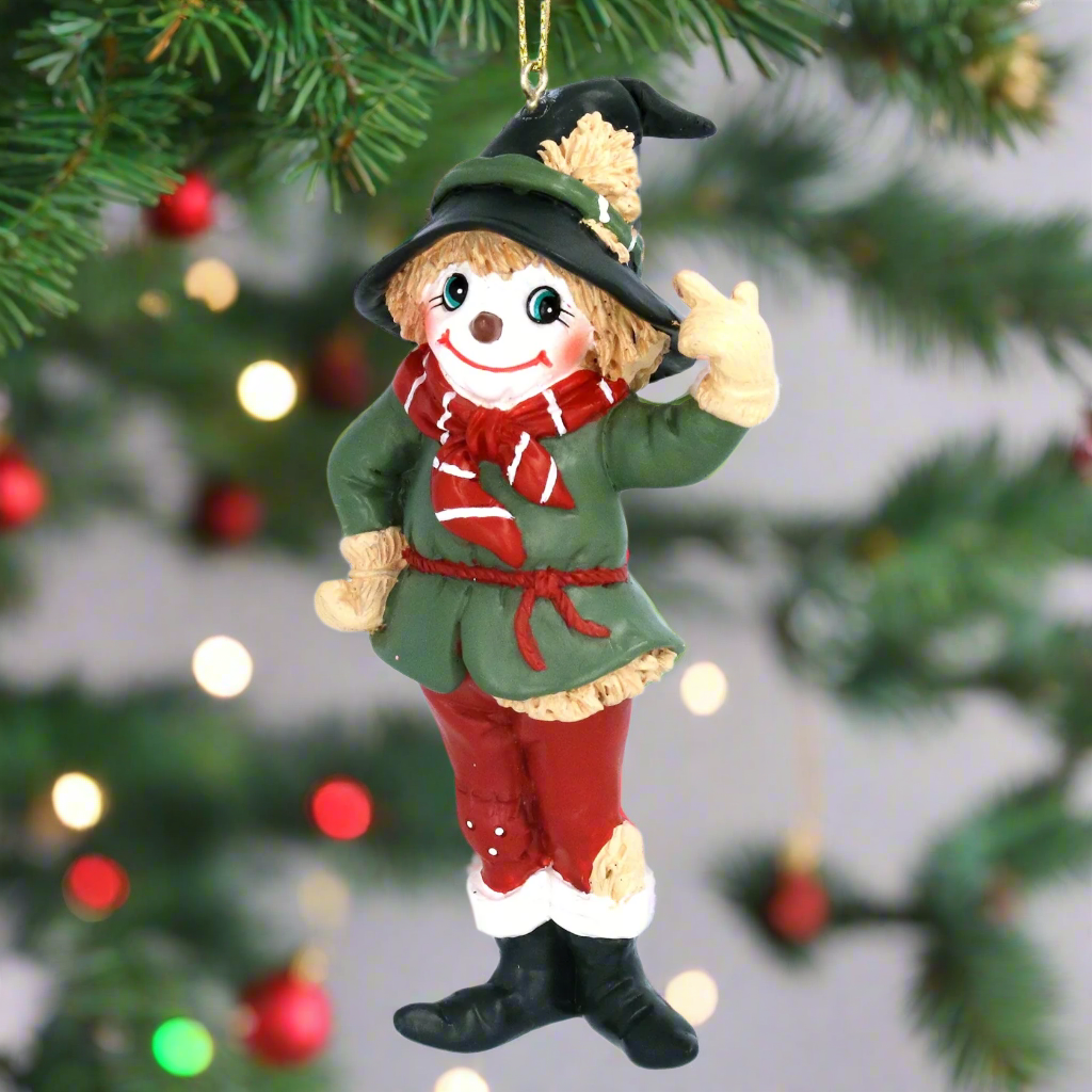 A hanging Christmas tree decoration depicting a Scarecrow from the Wizard of Oz, with green coat, red scarf, and black boots.