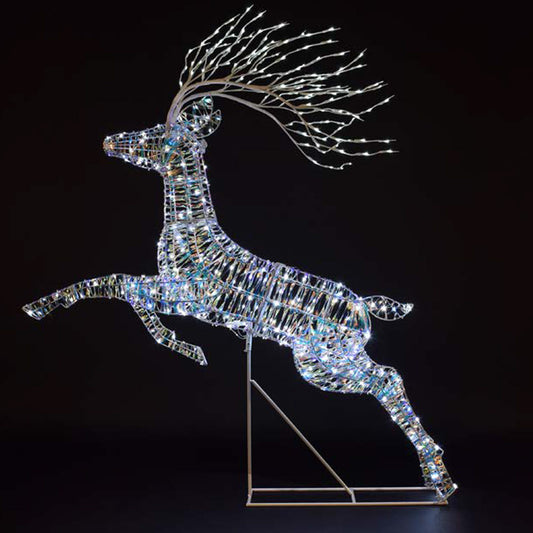 A leaping deer LED light decoration made of iridescent reflective segments, with branching antlers lit by small white lights, standing on a metal support against a black background.