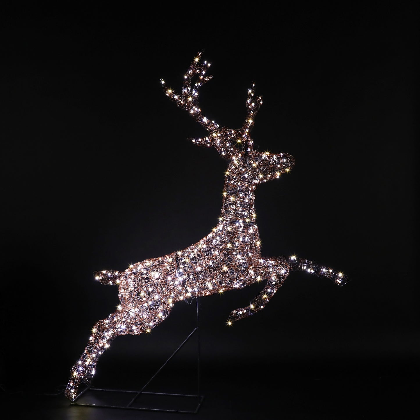 A sparkling, light-up deer sculpture in a leaping pose, illuminated with warm white lights against a solid black background.