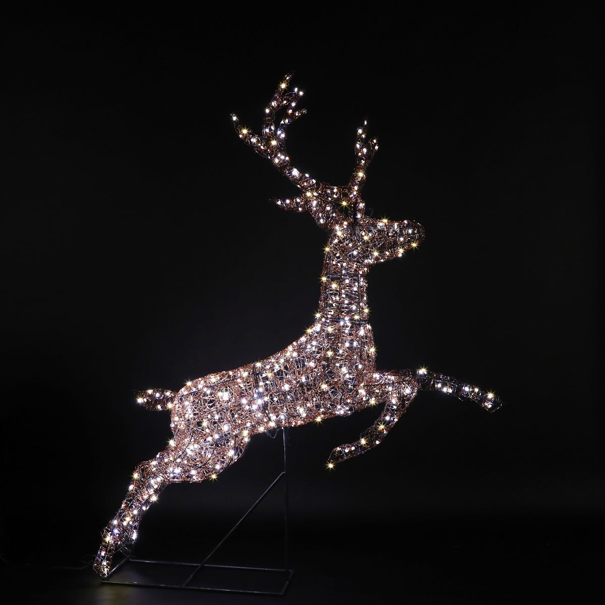 A sparkling, light-up deer sculpture in a leaping pose, illuminated with warm white lights against a solid black background.