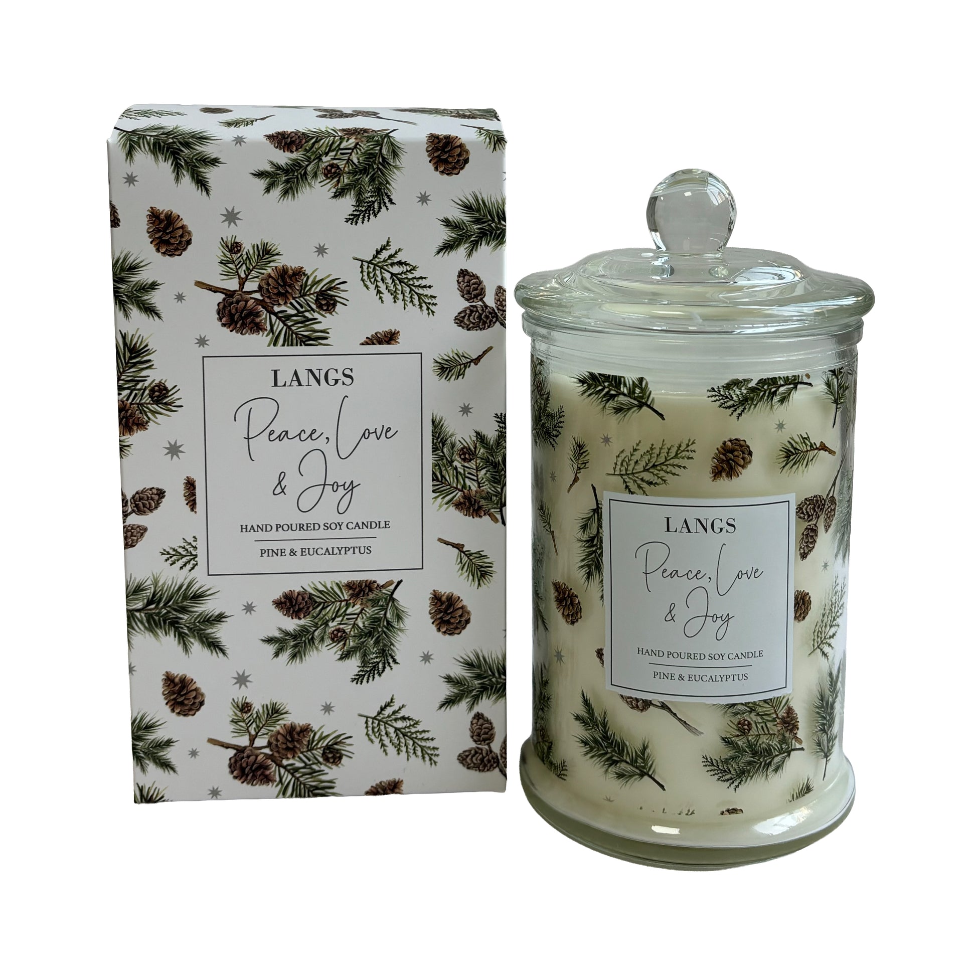 Scented candle in a clear glass jar with a glass lid, shown next to its white box. The packaging and jar are decorated with a pine and eucalyptus pattern featuring green pine branches, brown pinecones, and small snowflakes on a white background.