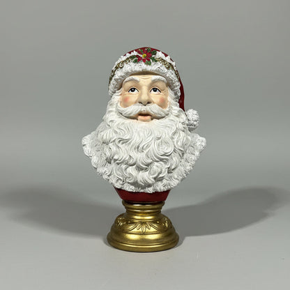 A Santa Claus bust figurine with a white beard, red hat, and gold base, plain background