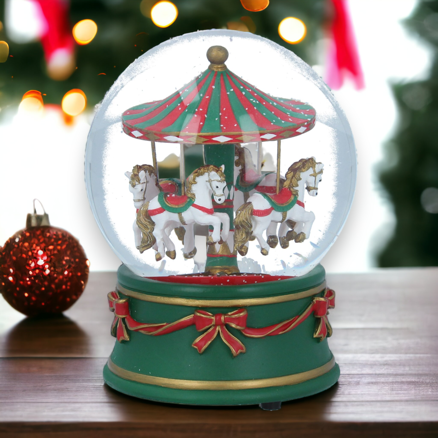 A musical Christmas snow globe featuring a carousel with horses and riders, encased in a transparent glass sphere with a green and red decorative frame.