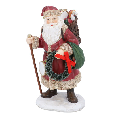 Decorative figurine of a Santa Claus holding a wreath and walking stick on a white background