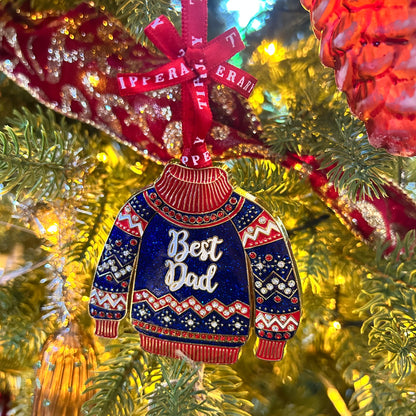 Decorative ornament shaped like a blue sweater with 'Best Dad' text, hanging on a Christmas tree.