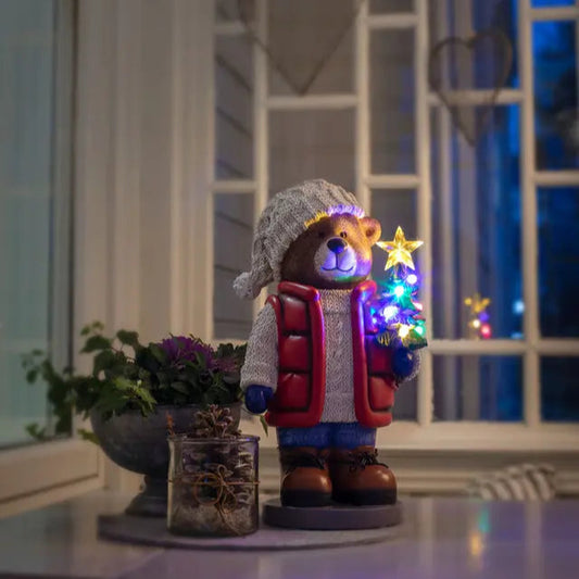 Decorative bear figurine with lights and star in a cozy setting.