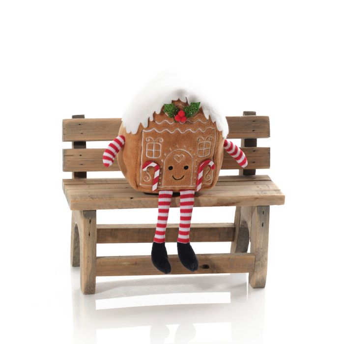 A fabric shelf sitter resembling a gingerbread house with a striped decoration, sitting on a wooden bench.