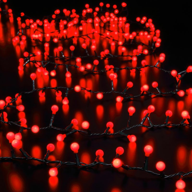 A close-up of illuminated red LED Christmas lights with a green cable against a black background.