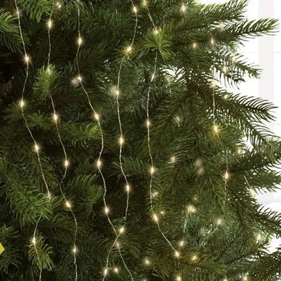 A close-up of a Christmas tree decorated with warm white silver LED lights.