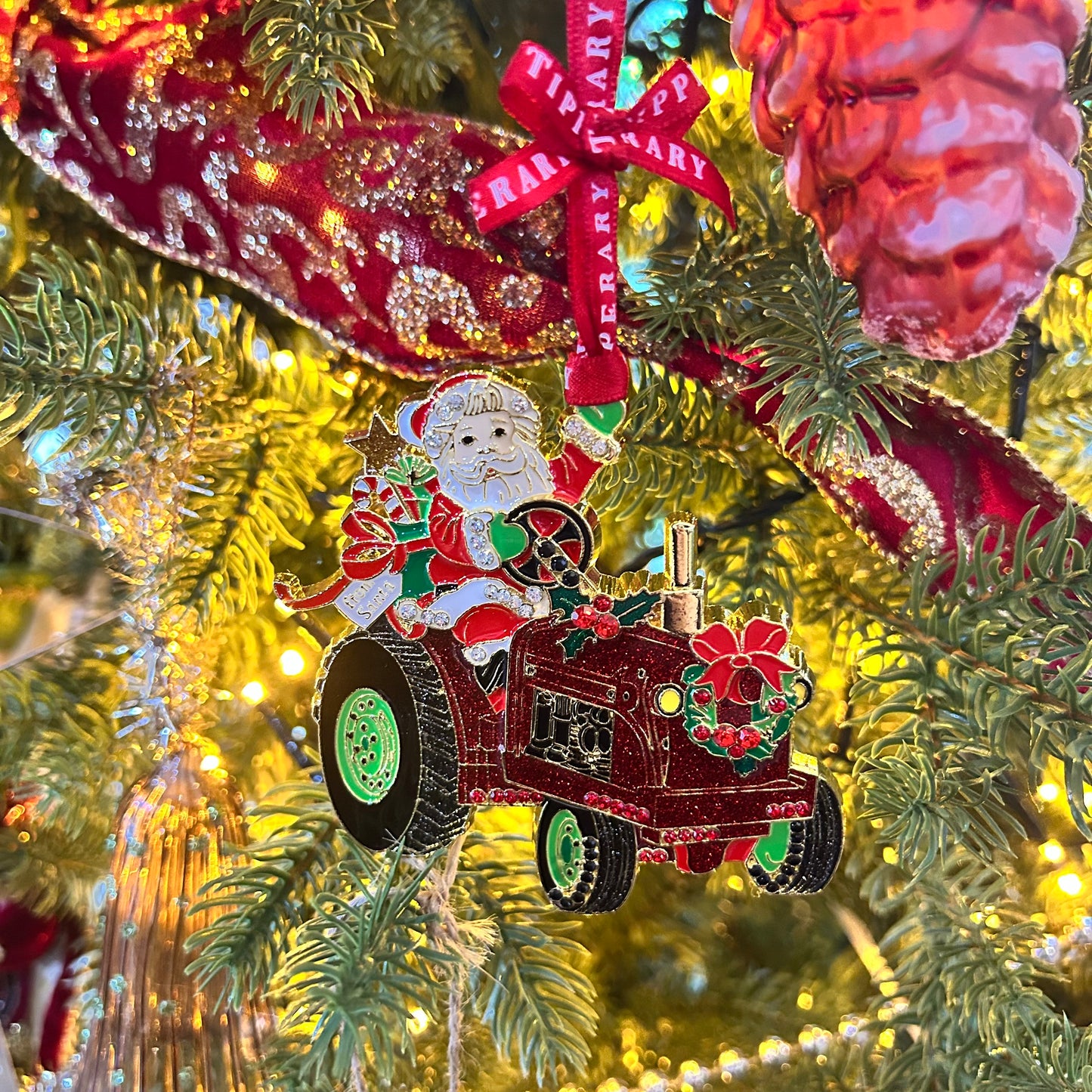 Decorative Christmas ornament with Santa driving a tractor on a tree.