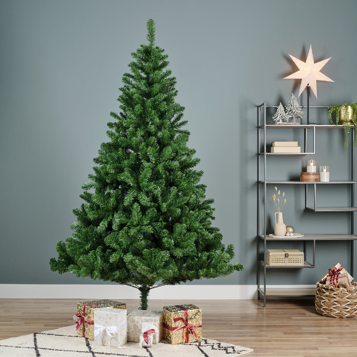 A 6ft tall artificial Christmas tree with green PVC foliage, placed in a home setting with decorative items and a star-shaped light hanging on the wall in the background.