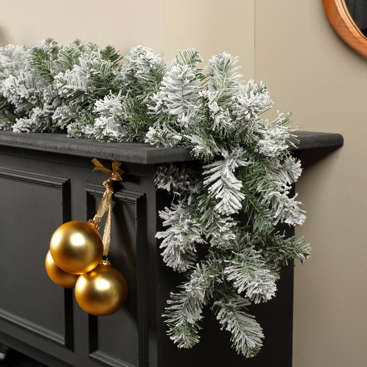A festive garland with silver branches and gold balls hung on a dark wall.