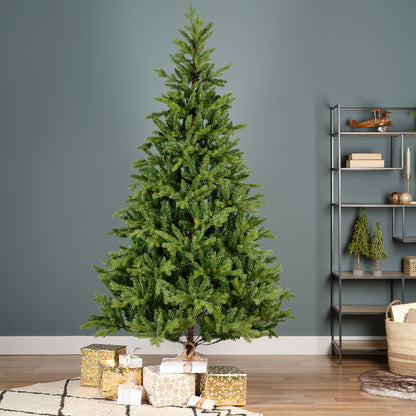 A realistic green pine Christmas tree with metal feet, placed on a decorative mat, surrounded by holiday decorations and books in the background.