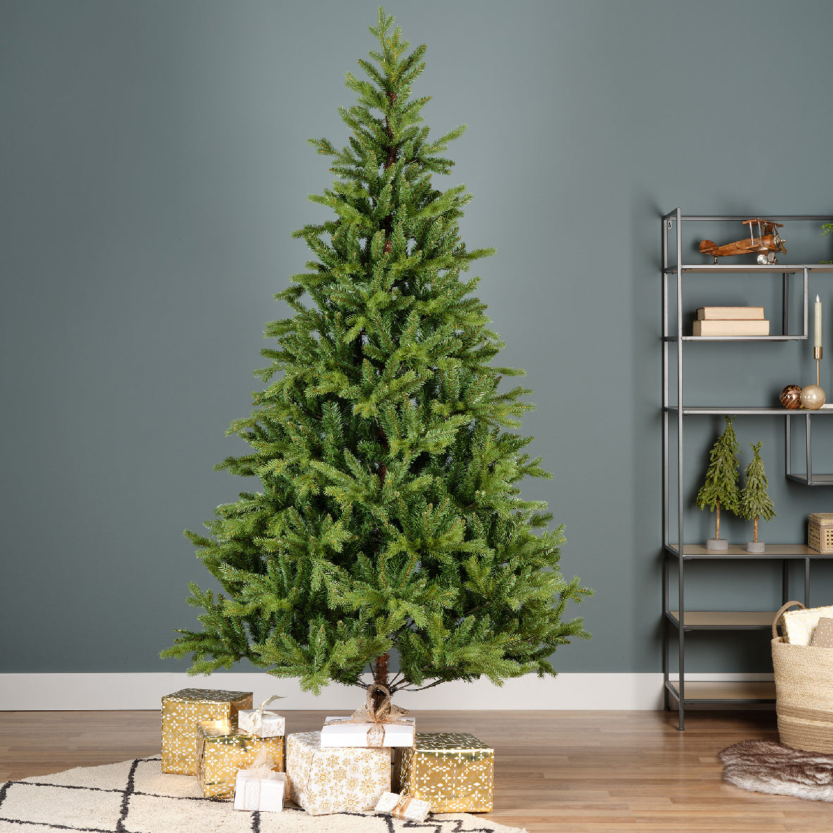 A 6ft/180cm artificial Christmas tree with green PE and PVC foliage, placed in a room with Christmas decorations and a metal foot.