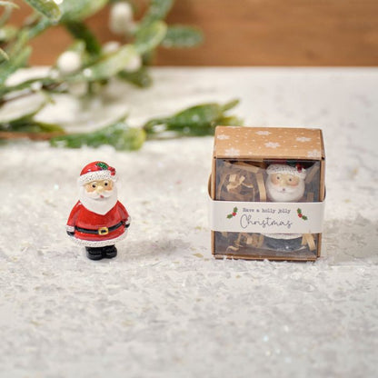 A small resin ornament featuring a Santa Claus figure next to a Christmas-themed box with a snowflake design.