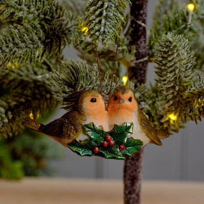 Two robin figurines with holly and berries hanging as a decoration.