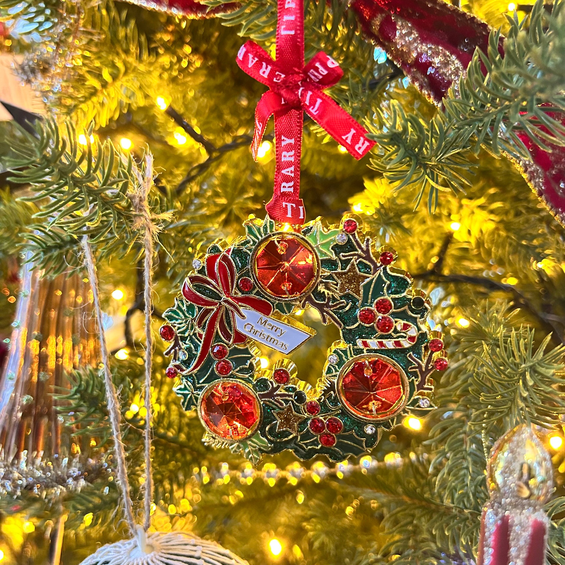 Decorative Christmas ornament on a tree with lights in the background