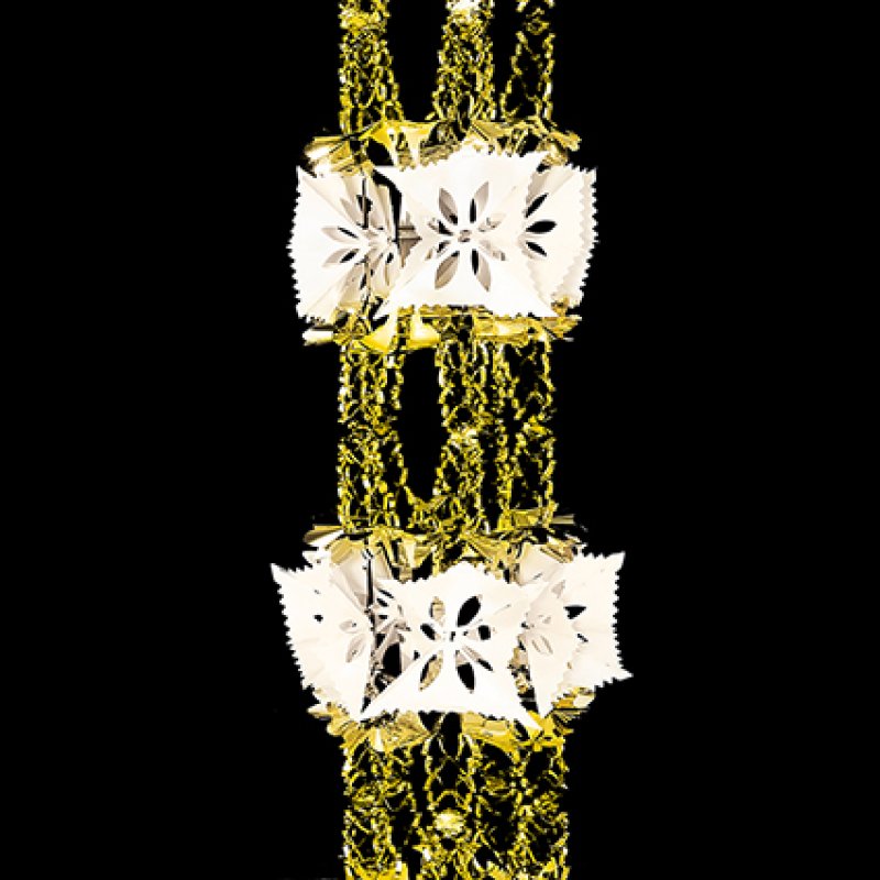 A close-up of a gold and ivory retro foil garland, snowflake-like decorative charms, set against a solid black background.