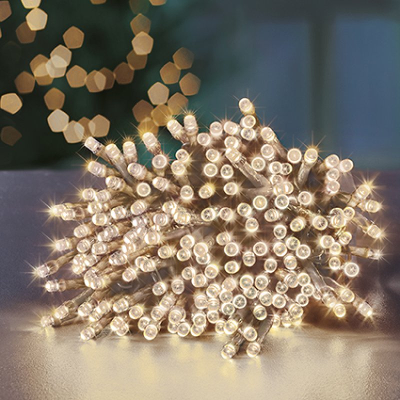 Warm white LED string lights bunch on a reflective surface, with soft golden  lights blurred in the background.