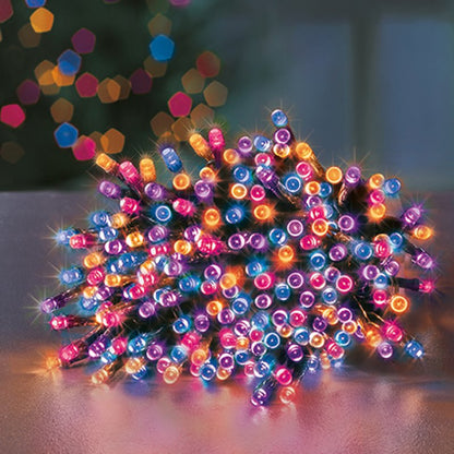 A pile of rainbow colour LED fairy string lights glowing with pink, blue, orange, and purple lights on a dark wire, set against a blurred festive background with bokeh.