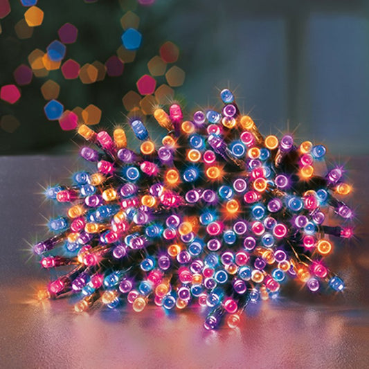 A pile of rainbow colour LED fairy string lights glowing with pink, blue, orange, and purple lights on a dark wire, set against a blurred festive background with bokeh.