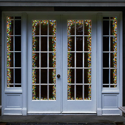 White French door windows decorated with vertical strands of multicolor Christmas string lights, set against a dark background.