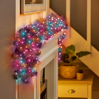 garland with rainbow lights draped over a white fireplace mantel in a cosy home setting.