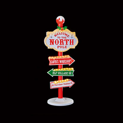 A decorative Christmas-themed North Pole signpost with multiple directional lights and signs reading 'Welcome to the North Pole,' 'Santa's Workshop,' 'Elf Village,' and 'Reindeer Stables' shown on a solid black background.